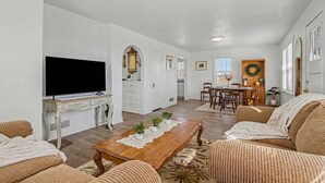 Un salon comprenant un téléviseur, un canapé, une table basse et un coin repas avec des chaises et une table.