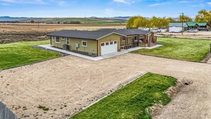A single-story house with a garage, a covered porch, and a large driveway. - Big Foot Ranch Retreat – Spacious Idaho Home w/ View (Melba)