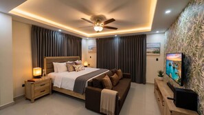 A modern bedroom with a bed, a sofa, a TV, and a ceiling fan. - Villa Shorys: Free Electricity | 12Pax | Pool+Jacuzzi | A/C | Covered Parking (Punta Cana)