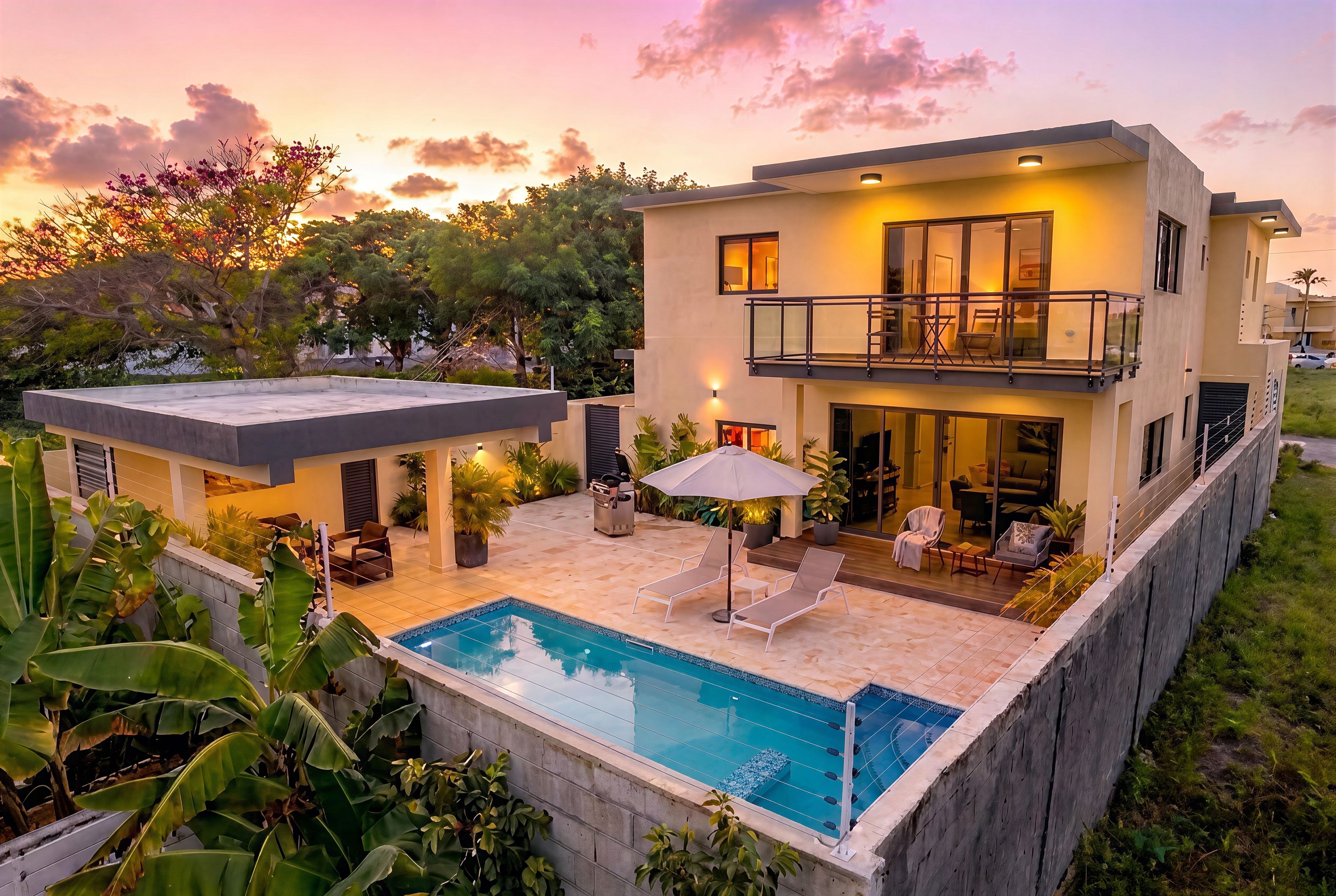 A modern two-story house with a swimming pool, outdoor seating, and a balcony.