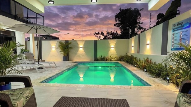 Piscina com mural do pôr do sol, área de estar externa e ventilador de teto.