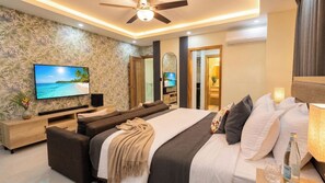 A modern hotel room with a large bed, a TV, a sofa, and a ceiling fan. - Villa Shorys: Free Electricity | 12Pax | Pool+Jacuzzi | A/C | Covered Parking (Punta Cana)