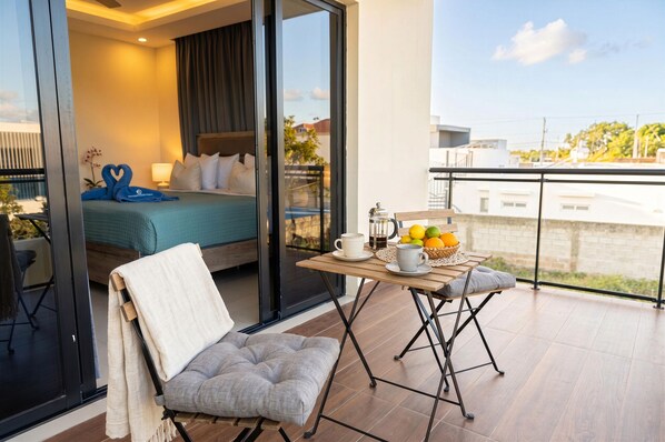 A balcony with a table set for breakfast, a bed with a view, and a chair. - Villa Shorys: Free Electricity | 12Pax | Pool+Jacuzzi | A/C | Covered Parking (Punta Cana)