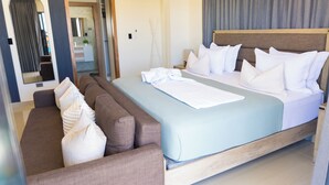 Quarto com cama, sofá, espelho e banheiro ao fundo.