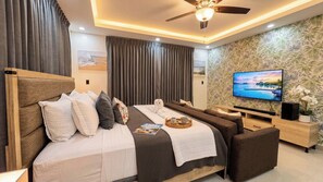 A modern hotel room with a bed, sofa, TV, and a decorative wall. - Villa Shorys: Free Electricity | 12Pax | Pool+Jacuzzi | A/C | Covered Parking (Punta Cana)