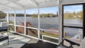 Un espace extérieur abrité avec vue sur un lac, un banc et une porte donnant accès à l’eau.