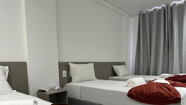 A hotel room with two beds, a nightstand, and a window with curtains. - Areião Park Hotel (Goiânia)