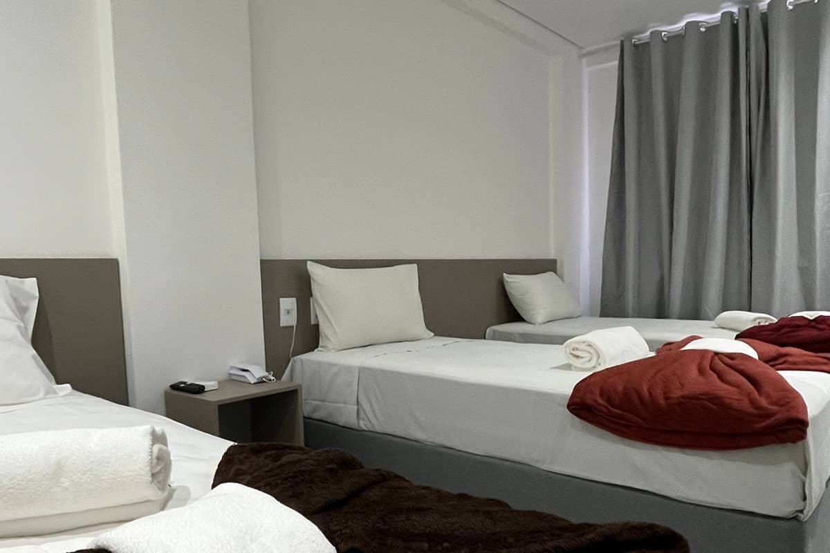 Une chambre d’hôtel avec deux lits, une table de chevet et une fenêtre avec des rideaux.