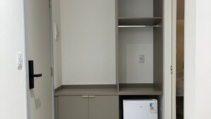 A small, well-lit room with a door, a refrigerator, and a built-in shelving unit. - Areião Park Hotel (Goiânia)
