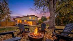 Ein Garten mit Feuerstelle, Sitzgelegenheiten im Freien und einem Haus im Hintergrund.