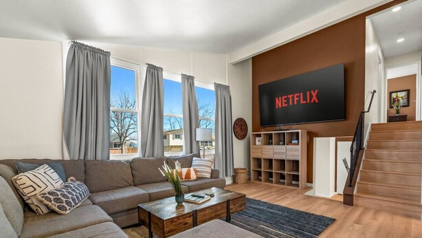 Ein modernes Wohnzimmer mit einer Couch, einem Couchtisch und einem an der Wand befestigten Flachbildfernseher.