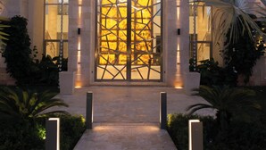 Un edificio moderno con un amplio ventanal, fachada de piedra y un camino que conduce a la entrada.