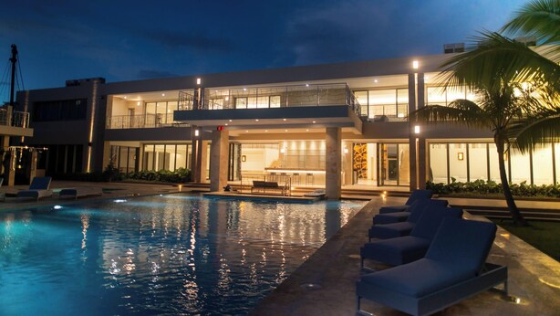 Un hotel moderno con piscina, sillas de descanso y un área exterior techada.