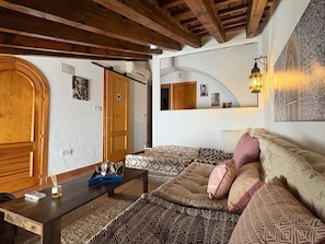 A cozy living room with a wooden bench, a sofa, and a coffee table. - Apartamento La Muralla -  Ole Solutions (Jerez de la Frontera)