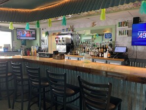 Eine Bar mit Tresen, Stühlen, einem Fernseher und verschiedenen Flaschen und Dosen.