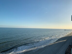 A beach with a pier extending into the water, a clear sky, and a sandy shoreline. - Incredible oceanfront condo with private balcony (Murrells Inlet)