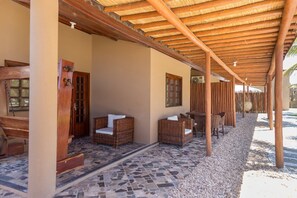 A covered outdoor seating area with wicker furniture and a stone-tiled floor.