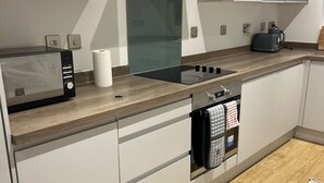 Una cocina moderna con microondas integrado, estufa y campana extractora.