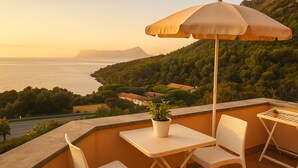 A balcony with a table, chairs, an umbrella, and a potted plant. - MARATEA, sea view apartment with pool use, 700 meters from the sea. (Maratea)