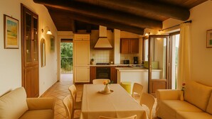A dining area with a table and chairs, a kitchen in the background, and a balcony with a view. - MARATEA, sea view apartment with pool use, 700 meters from the sea. (Maratea)