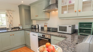 A kitchen with granite countertops, a dishwasher, a microwave, and a fruit bowl. - New Barn (Salisbury)