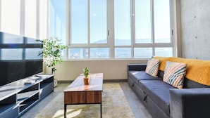 Una sala de estar moderna con un televisor grande, un sofá, una mesa de centro y una planta.