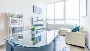 Una sala de estar moderna con una mesa de centro de vidrio, un sofá, un televisor y un ventanal grande.