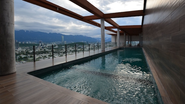 Una piscina interior con vista a la ciudad, vigas de madera y suelo de baldosas.