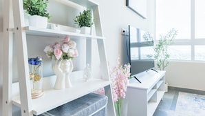 Una sala de estar moderna con un mueble blanco para el equipo de entretenimiento, un televisor de pantalla plana y un ventanal grande.