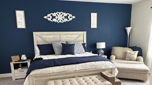 A bedroom with a bed, bedside tables, a nightstand, a bench, and a lamp. - Beautiful 4-bedroom house with AC in Ormond Beach (Ormond Beach)