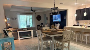 A modern kitchen with a dining area, a TV, and a ceiling fan. - Beautiful 4-bedroom house with AC in Ormond Beach (Ormond Beach)