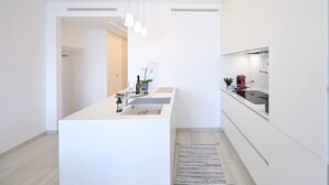 A modern kitchen with a central island, white cabinetry, pendant lighting, and a small potted plant. - Serenity Lakefront 2 Bedrooms Retreat in Lugano (Lugano)