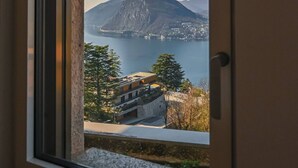 A window with a view of a mountain and a body of water. - Serenity Lakefront 2 Bedrooms Retreat in Lugano (Lugano)