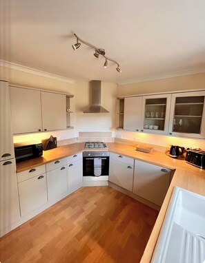 Una cocina compacta con armarios blancos, horno empotrado, estufa y microondas.