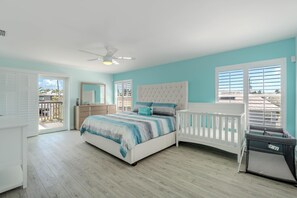 Ein Schlafzimmer mit einem Bett, einem Babybett, einem Deckenventilator und Blick ins Freie.