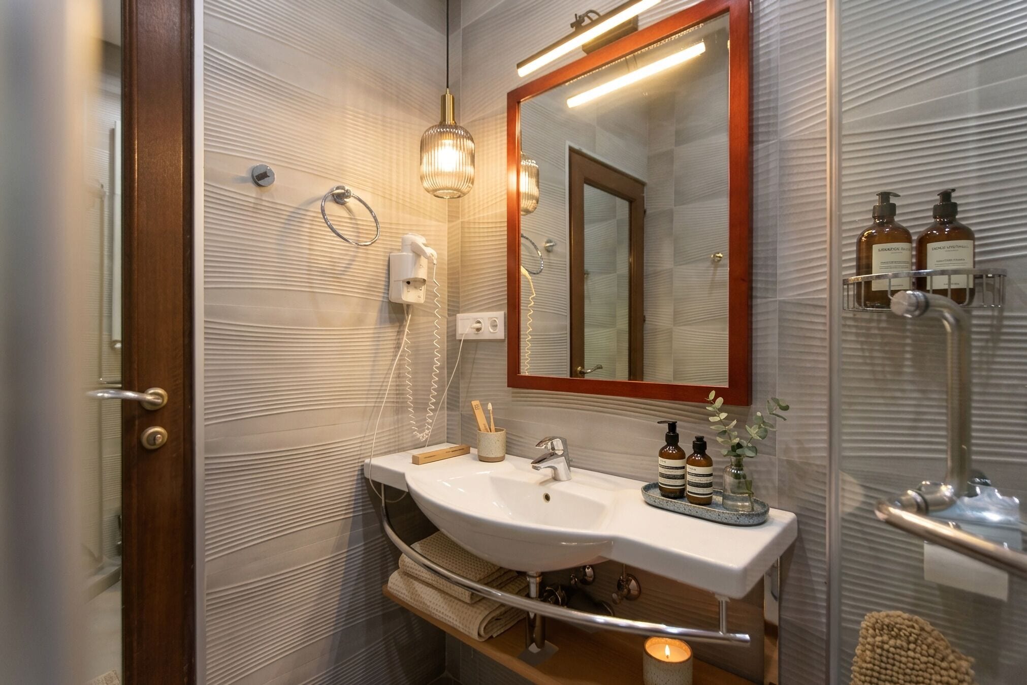 A bathroom with a white sink, a mirror, a towel rack, and a shower area.