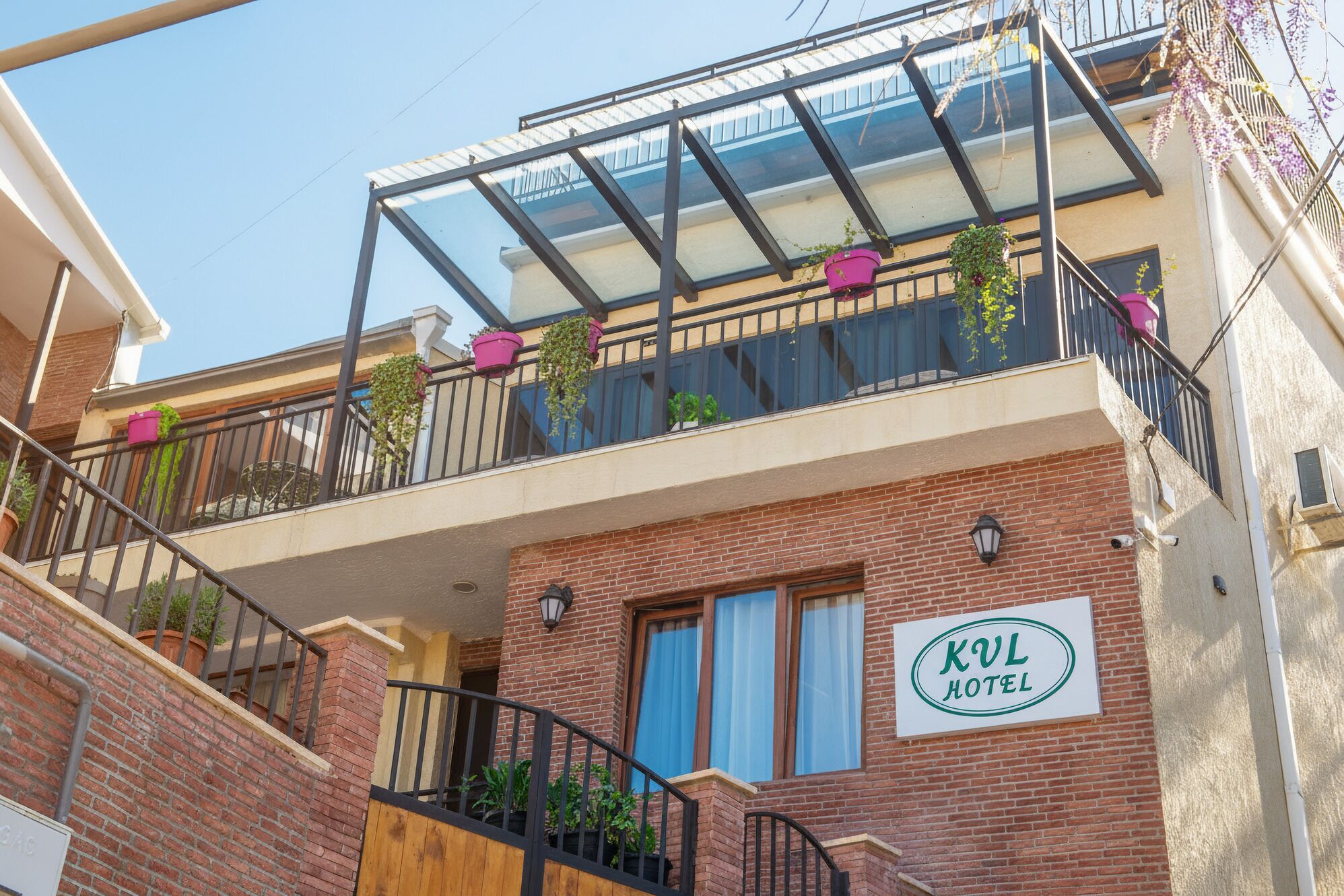 A hotel with a balcony, potted plants, and a sign indicating it's the KUL HOTEL.