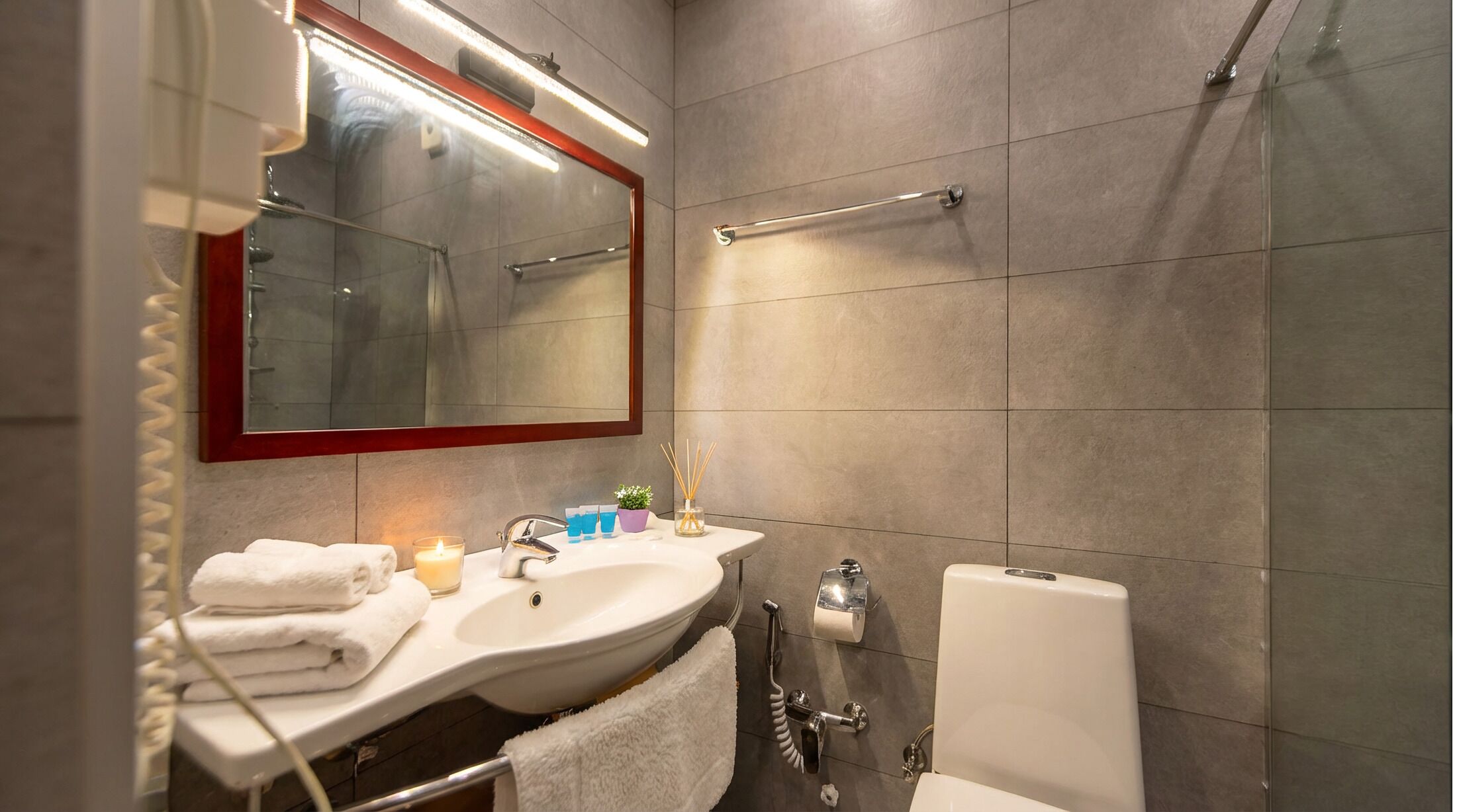 A bathroom with a sink, mirror, towel rack, and toilet.