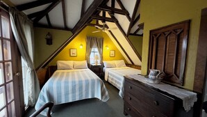 A room with two beds, a wooden dresser, and a window with curtains.
