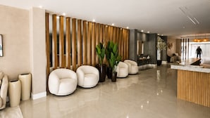 A spacious lobby with a reception desk, seating area, and a large potted plant. - Apartamento em Cond. de Luxo  (Arraial do Cabo)