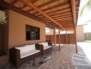 A covered outdoor seating area with wicker furniture and a thatched roof.