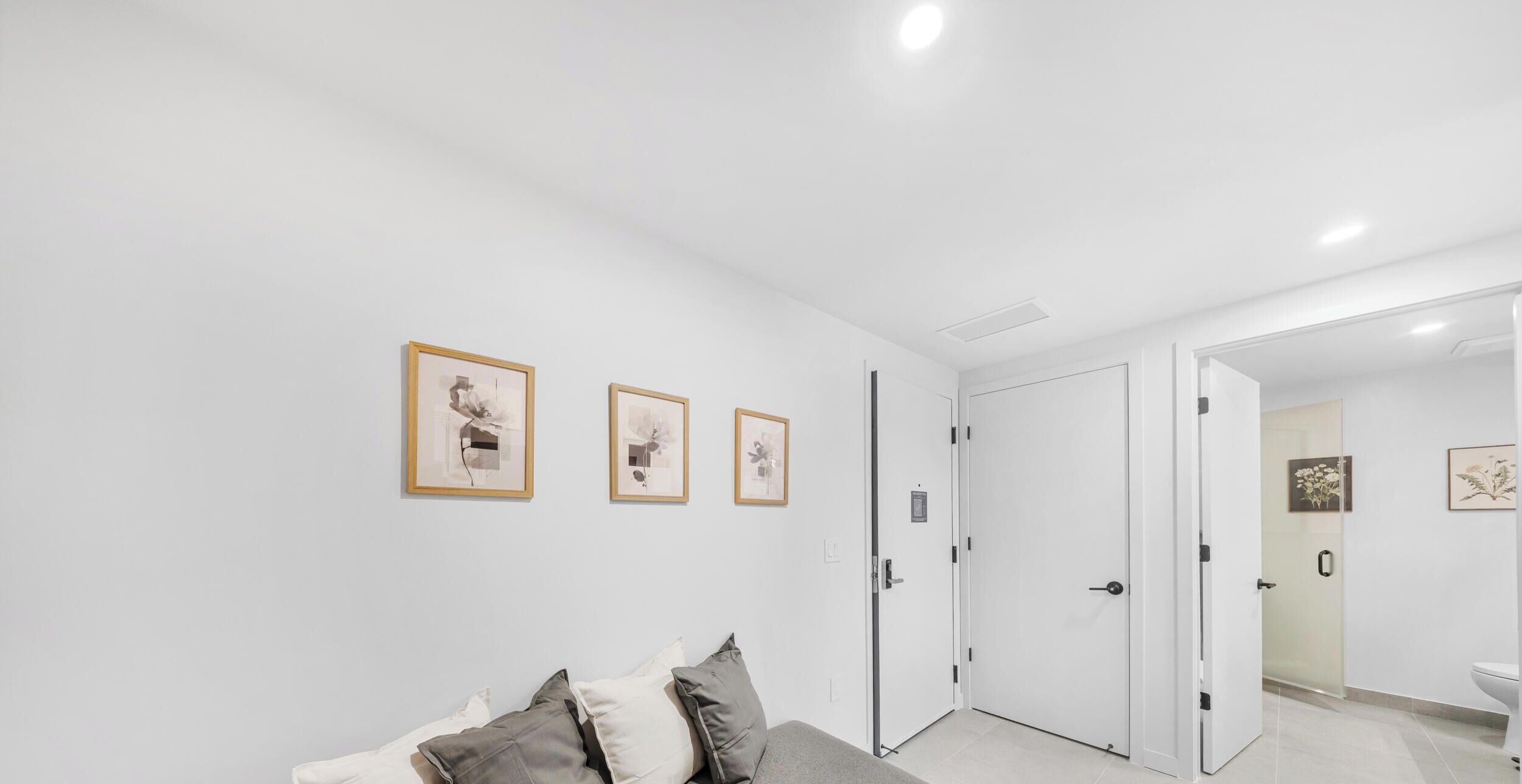 Une pièce comprenant un lit, une porte et une salle de bain visible à travers une porte en verre.