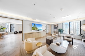 A modern living room with a flat-screen TV, comfortable seating, a dining area, and large windows with a city view. - Downtown Miami Getaway with City Views (Miami)