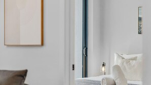 Ett modernt hotellrum med en säng, ett sängbord med en lampa och en inramad tavla på väggen.