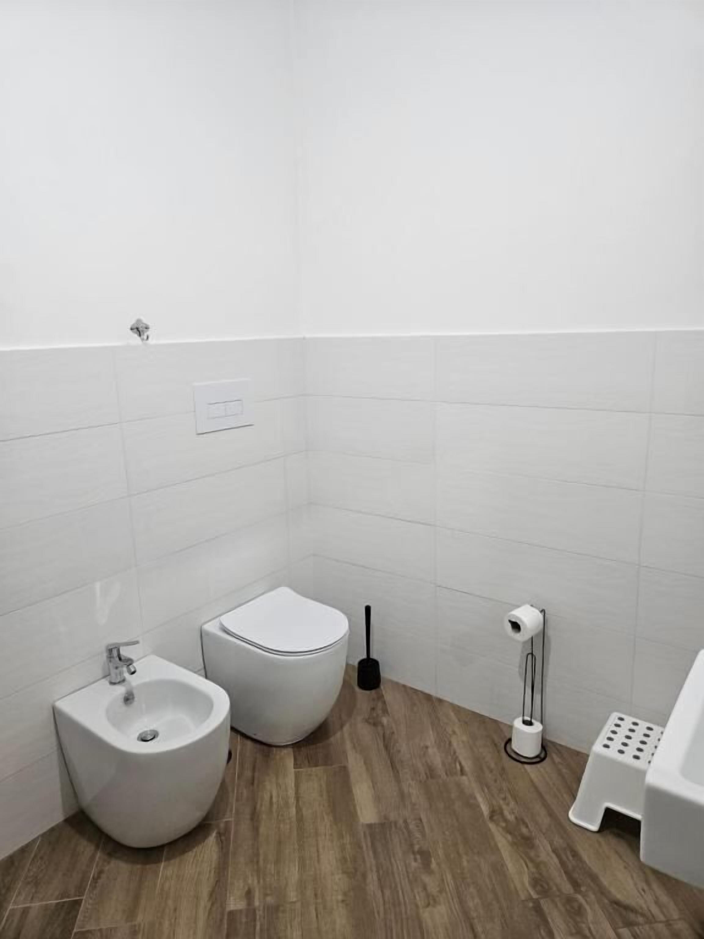Un baño pequeño y moderno con un bidé, inodoro y un lavamanos reducido.
