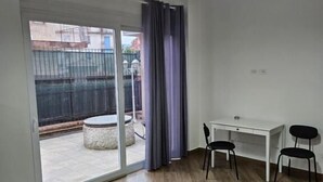 A room with a sliding glass door leading to an outdoor area, a white desk with two chairs, and a hanging pendant light. - Onda Blu (Agropoli)