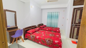 A bedroom with a bed, a desk with a chair, a mirror, and a window with curtains. - Hotel Grand Nuria (Habiganj Sadar)
