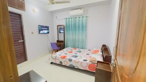 A bedroom with a bed, a TV, a mirror, a window with curtains, and a ceiling fan. - Hotel Grand Nuria (Habiganj Sadar)