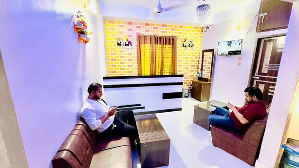 A living room with a brick wall, a television, and two sofas. - Hotel Grand Nuria (Habiganj Sadar)