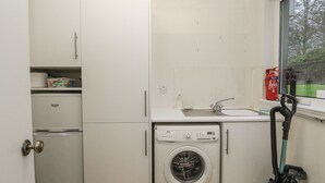 Cocina compacta con lavadora, un lavabo y ventana con vistas.